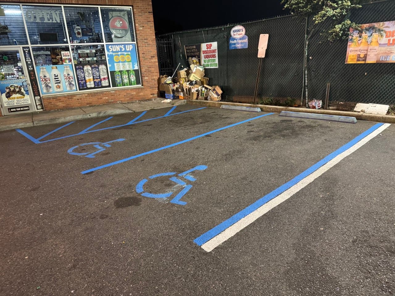 Freshly painted ADA-compliant accessible parking spaces with blue wheelchair symbols, access aisle hash marks, and white boundary lines by Sterling Pavement