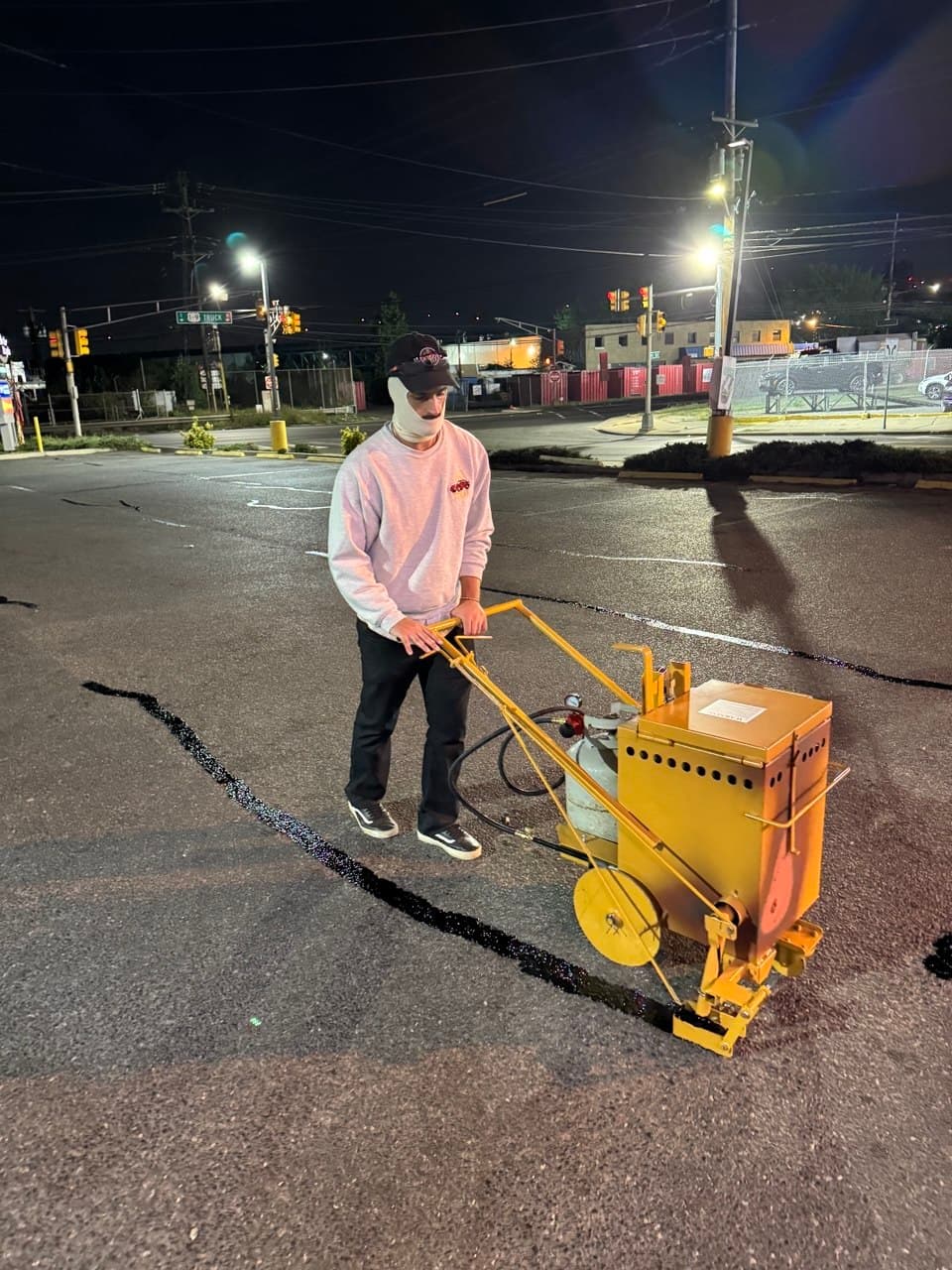 Sterling Pavement crew member using a hot-pour crack filling machine to seal cracks in a commercial parking lot before sealcoating